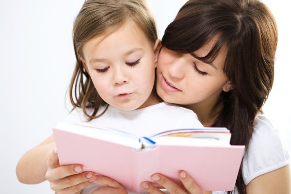 Mother is reading book with her daughter, indoor shoot