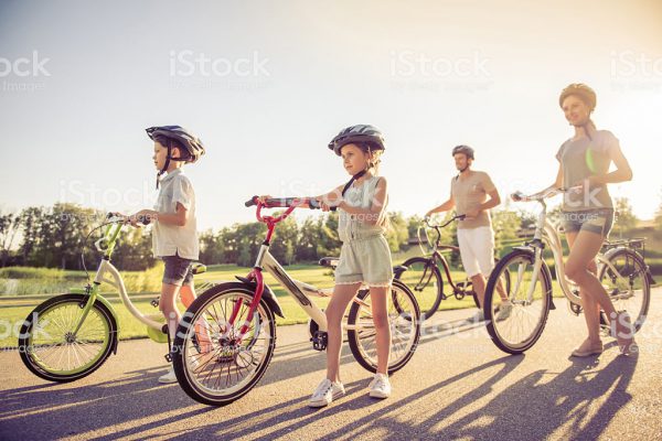 Happy family is riding bikes outdoors and smiling, full length